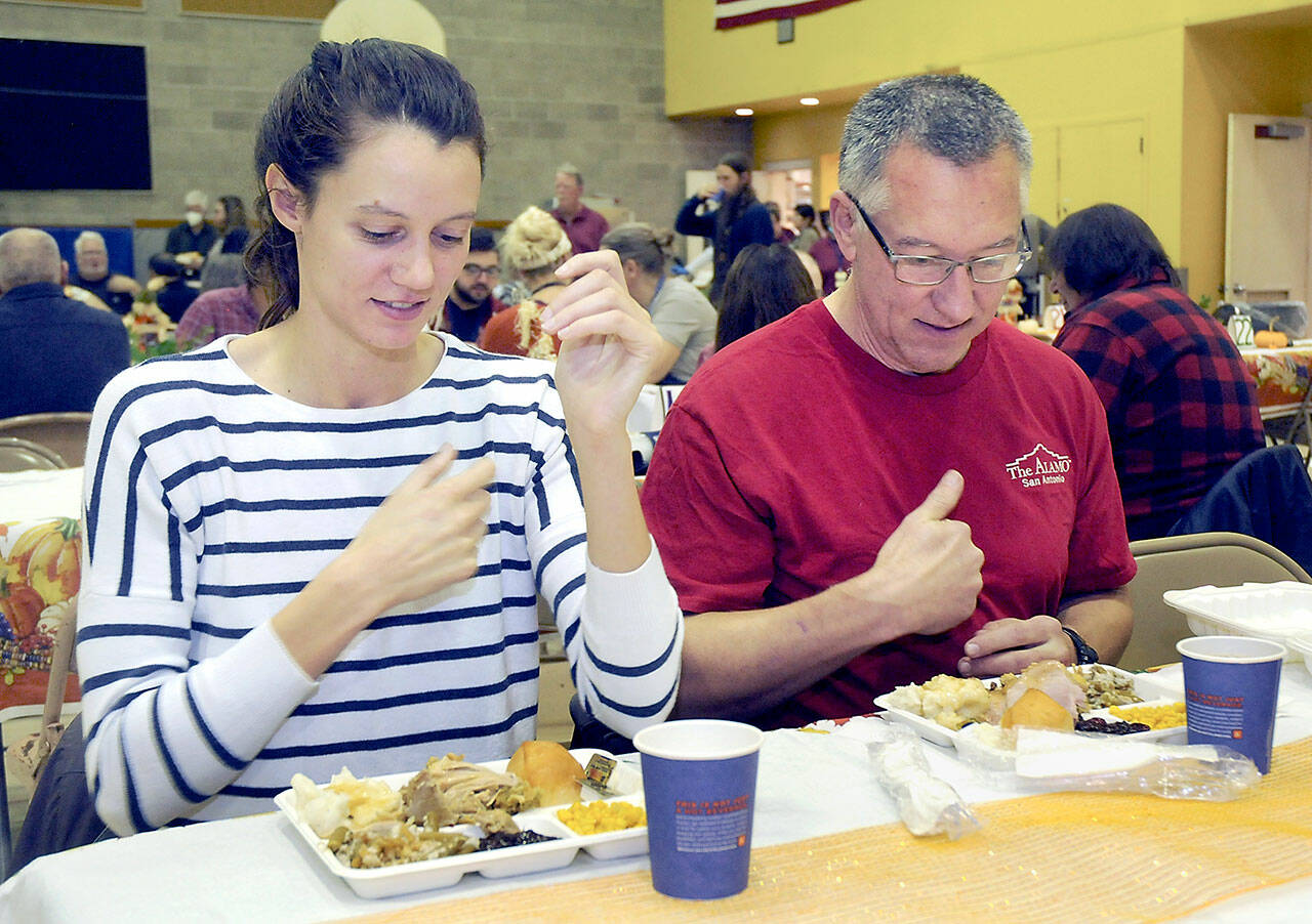 Cecilia Stevenson, of Dallas, left, and her father, Will Stevenson of Port Angeles, say a blessing before enjoying a Thanksgiving meal in the fellowship hall of Queen of Angels Catholic Church in Port Angeles. The church offered a traditional Thanksgiving dinner for the community, with several hundred diners taking advantage of the in-house meal with numerous other dinners sent out for in-home dining. (Keith Thorpe/Peninsula Daily News)
