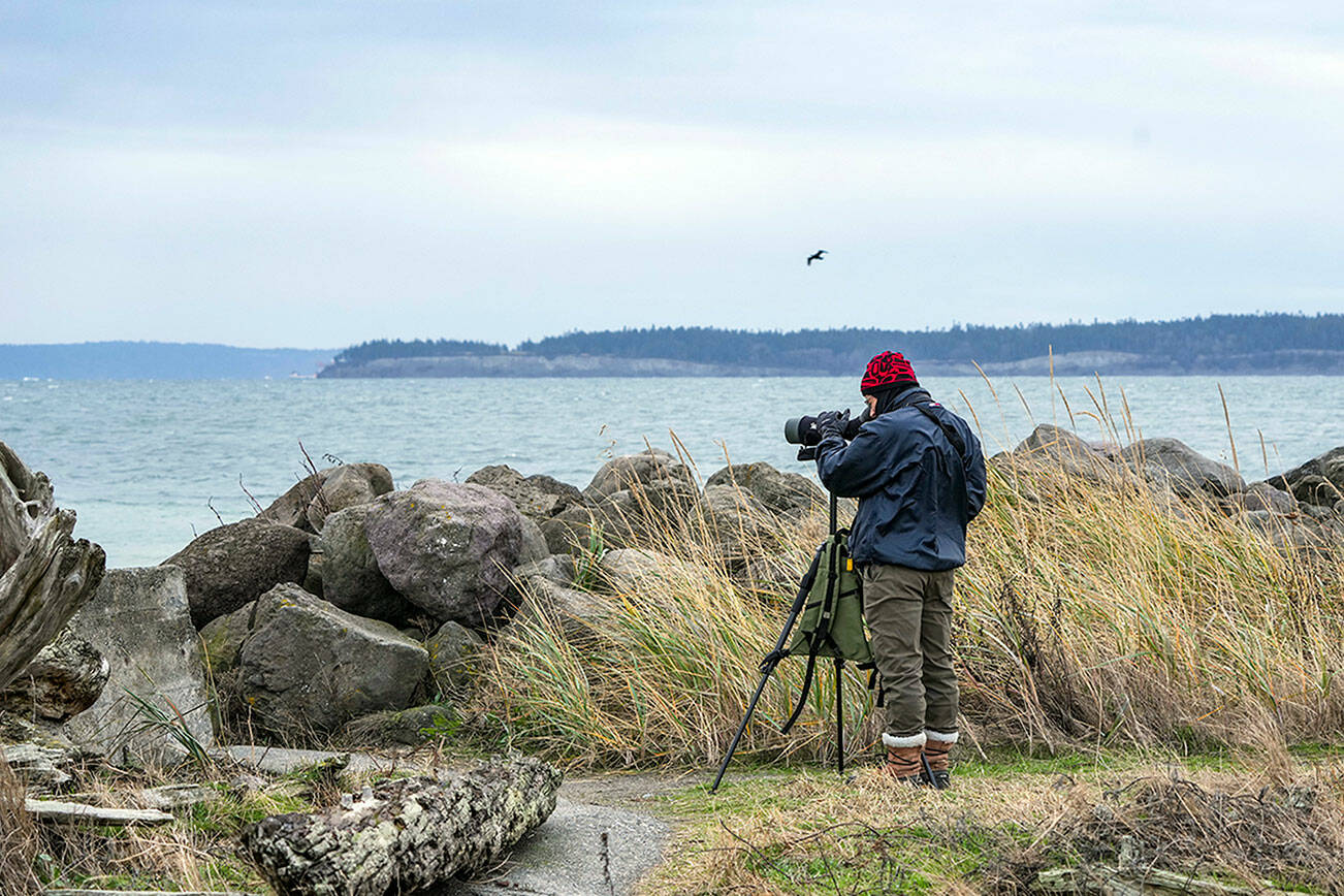 Steve Hampton of Port Townsend searches for birds in the Salish Sea at Point Wilson Lighthouse on Wednesday. “I just got here and the wind and choppy water don’t make for ideal conditions, but so far I’ve seen rhinoceros auklets and a Pacific loon,” Hampton said. (Steve Mullensky/for Peninsula Daily News)