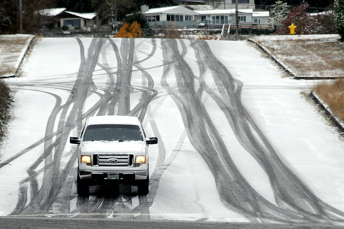A vehicle inches its way down a hill in the 100 block of South Liberty Street in Port Angeles after snow coated much of the North Olympic Peninsula on Thursday morning. Unsettled weather and chilly conditions are forecast into next week. (Keith Thorpe/Peninsula Daily News)