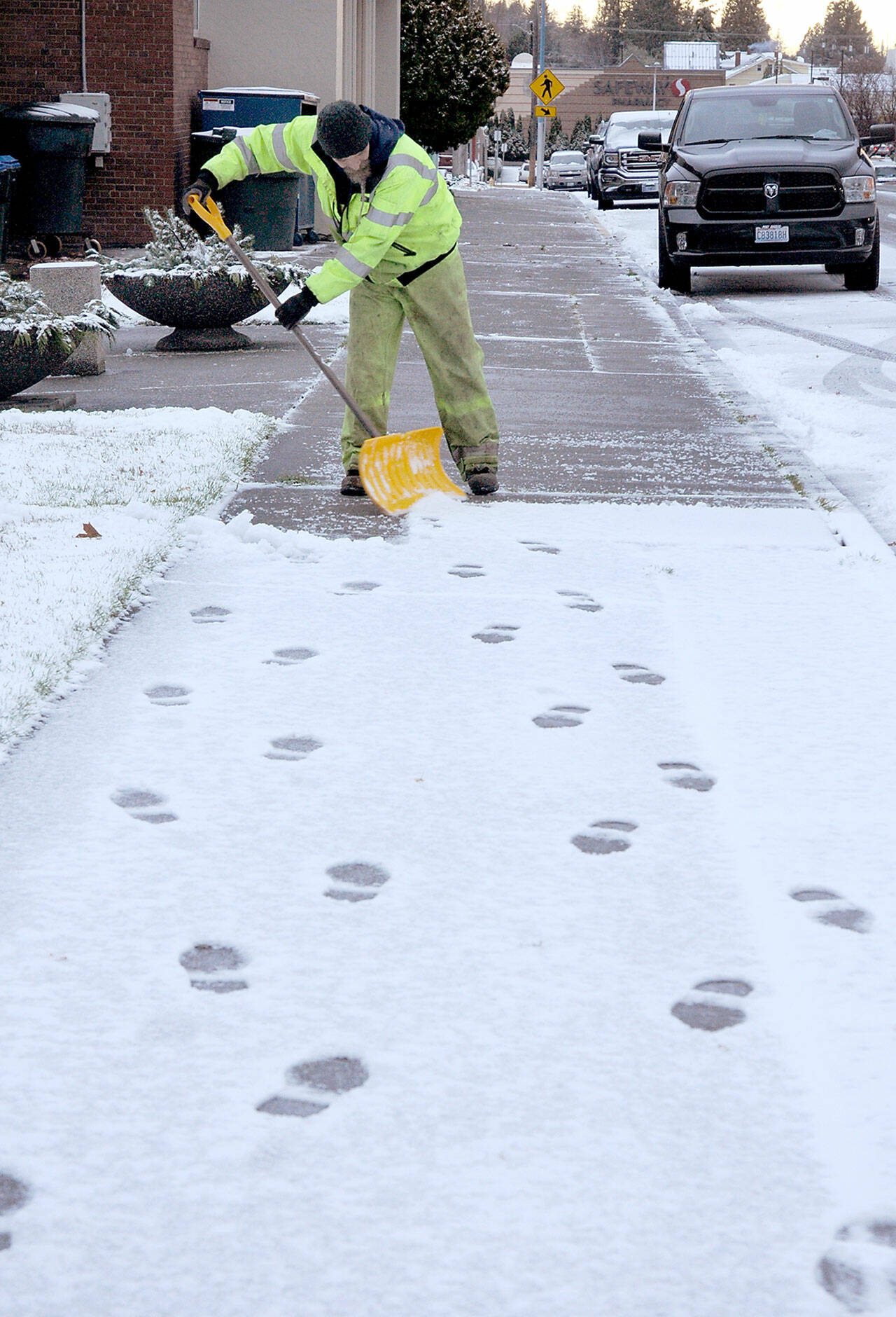 Port Angeles Parks and Recreation Department employee Darryl Anderson shovels a sidewalk along East Fourth Street near Vern Burton Community Center after snow coated much of the North Olympic Peninsula Thursday morning. (Keith Thorpe/Peninsula Daily News)