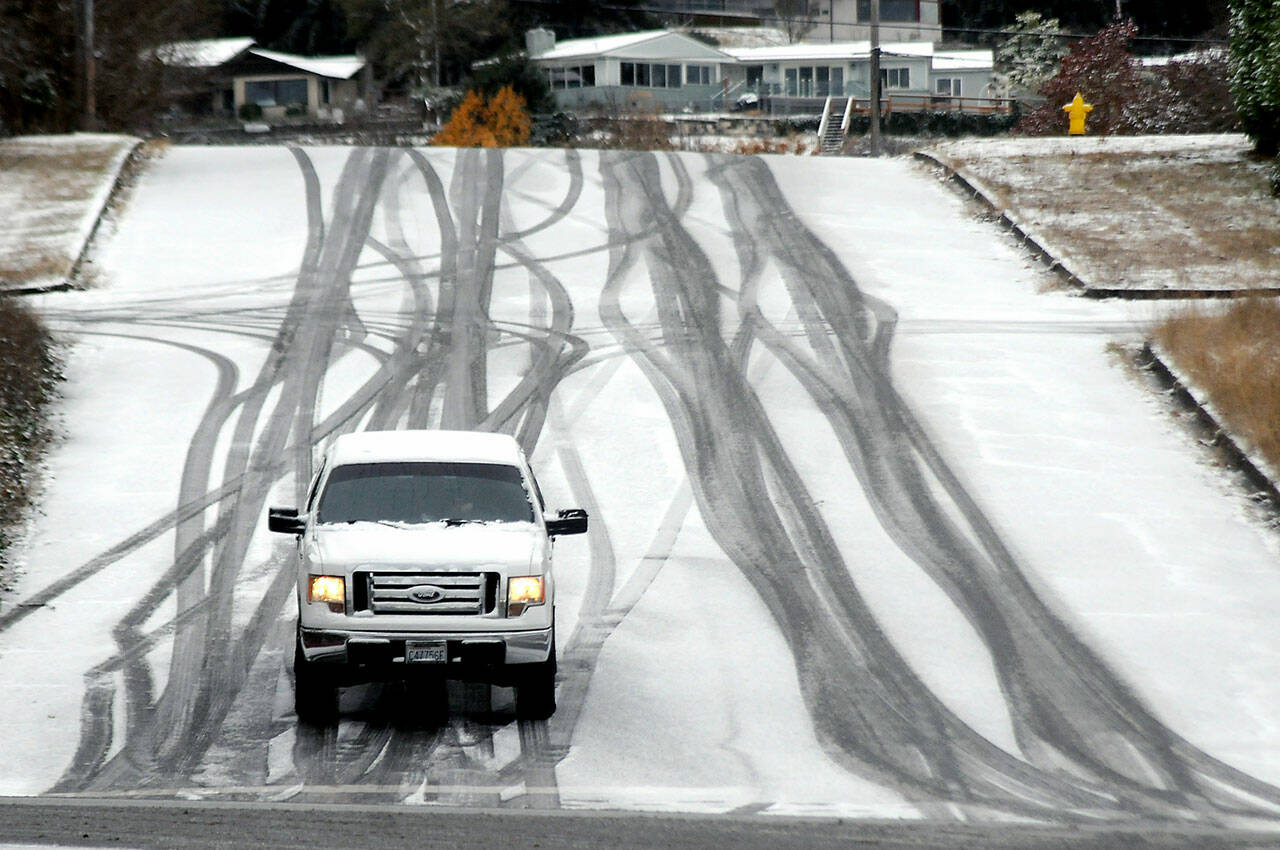 A vehicle inches its way down a hill in the 100 block of South Liberty Street in Port Angeles after snow coated much of the North Olympic Peninsula on Thursday morning. Unsettled weather and chilly conditions are forecast into next week. (Keith Thorpe/Peninsula Daily News)