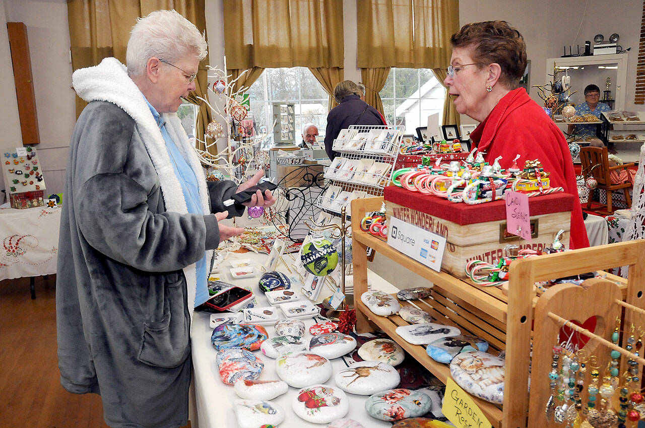 Sandie Kiehl of Sequim, left, makes a purchase from Pat Snyder of Sequim-based China Cat Creations during Saturday’s Homemade Christmas Craft Fair at the Sequim Prairie Grange near Carlsborg. (KEITH THORPE/PENINSULA DAILY NEWS)