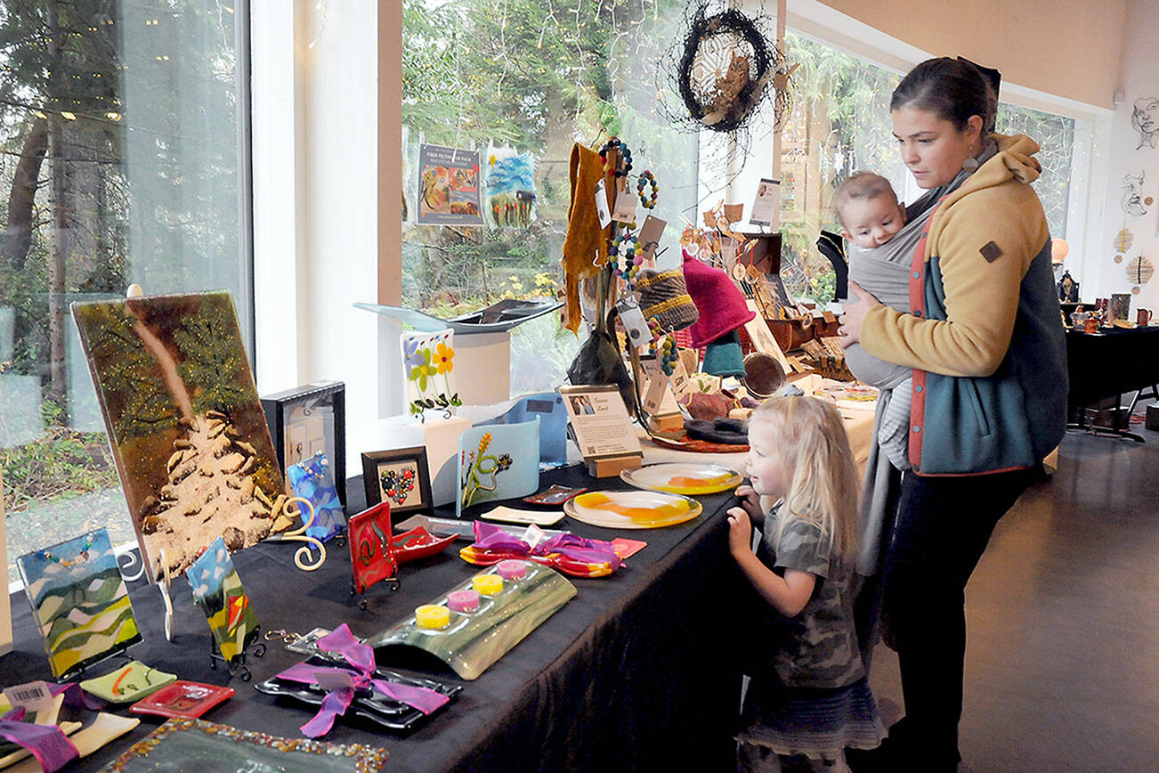 KEITH THORPE/PENINSULA DAILY NEWS
Molly Brown of Port Angeles, and her children, Lucy Brown, 3, and Oliver Brown, 5 months, examine a display of loally-produced art items for sale as gifts on Thursday during the holiday Makers Market at the Port Angeles Fine Arts Center. The market, open Thursday through Sunday from 11 a.m. to 5 p.m. and from 5 p.m. to 8 p.m. today and Dec. 16,  will observe extended. hours of 11 a.m. to 8 p.m. during the Wintertide Festival of Lights on Saturday..