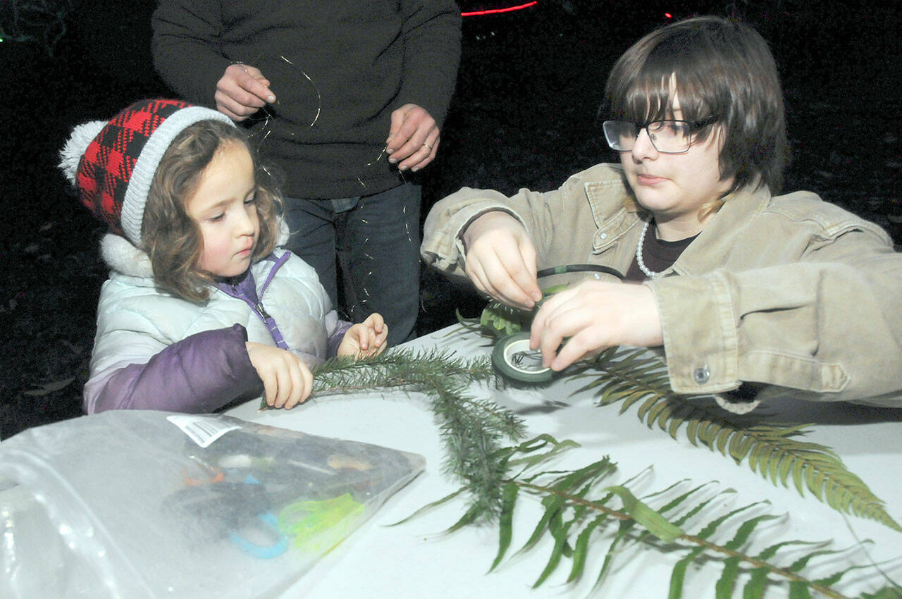 Amdiya Miller, 4, of Port Angeles gets assistance from Breanna Hedtke with making a decorative headdress at an activity table in Webster’s Woods at the Port Angeles Fine Arts Center during Saturday’s Wintertide Festival of Lights. (Keith Thorpe/Peninsula Daily News)