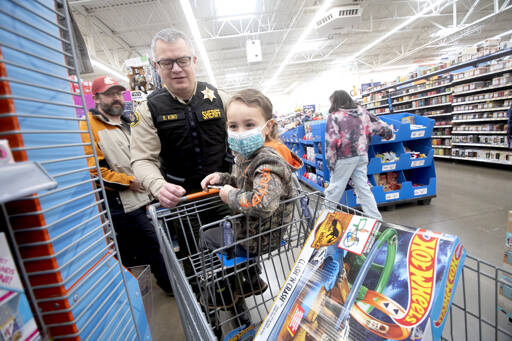 Brian King, the chief criminal deputy for the Clallam County Sheriff’s Office, is among more than 100 volunteers from a dozen agencies to participate in the Shop with a Hero program at Wal-Mart in Port Angeles. About 80 kids from the community got to go on a shopping spree with law enforcement officers from Port Angeles, Sequim and other agencies and spend $100 however they wished. They also had a chance to take photos with Santa, sip on hot chocolate, decorate cookies and see police vehicles up close. (Jesse Major/for Peninsula Daily News)
