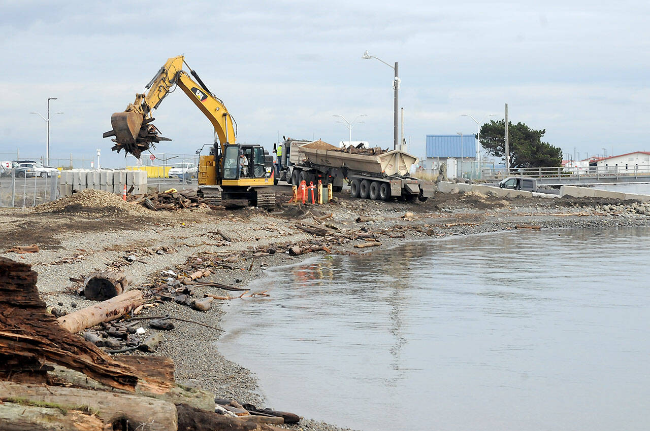 An excavator picks up woody debris for loading onto a nearby truck for disposal on Tuesday at the site of the former aquaculture site near the boat ramp on Ediz Hook in Port Angeles. (KEITH THORPE/PENINSULA DAILY NEWS)