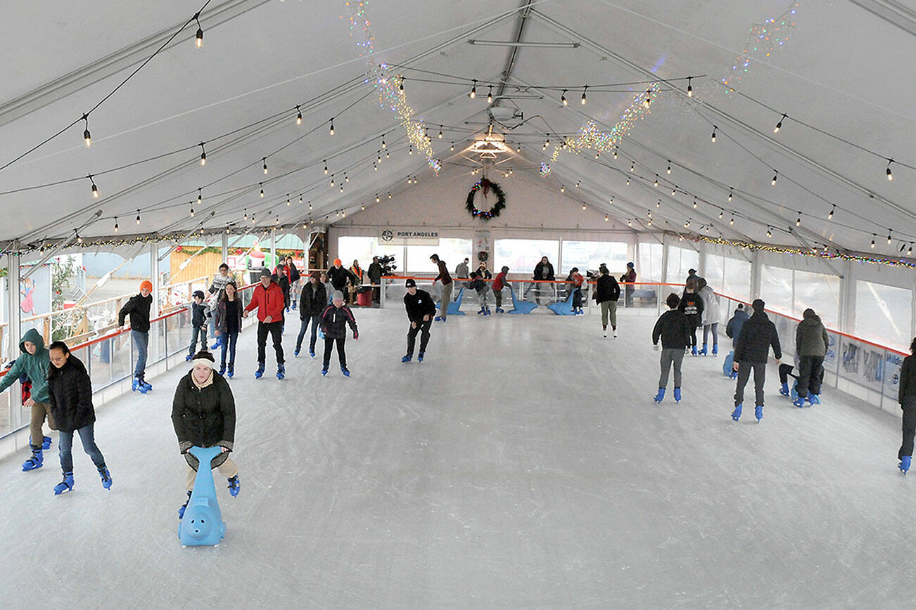 Skaters make their way around the rink at the Port Angeles Winter Ice Village on Thursday, assembled seasonally in a city parking lot in the 100 block of West Front Street. The same site is slated for a roller rink  next summer. (Keith Thorpe/Peninsula Daily News)
