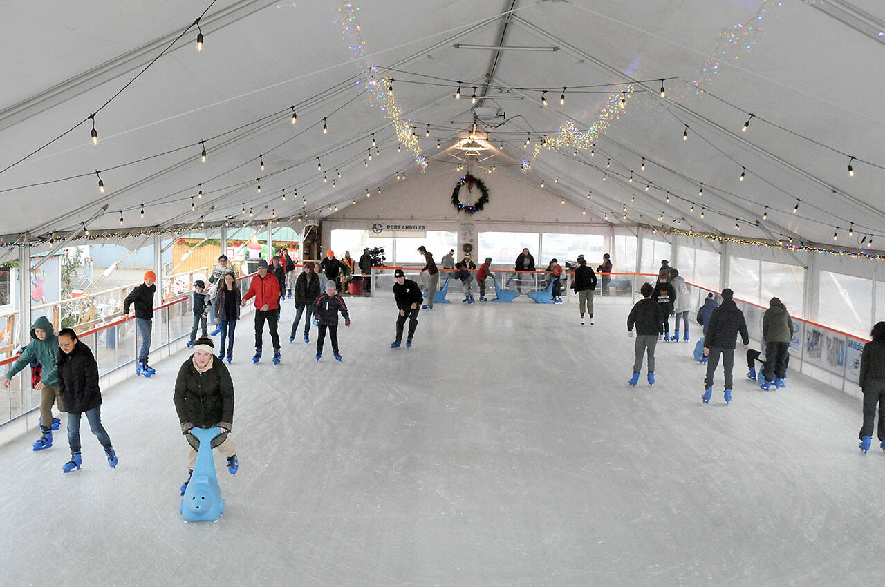 Skaters make their way around the rink at the Port Angeles Winter Ice Village on Thursday, assembled seasonally in a city parking lot in the 100 block of West Front Street. The same site is slated for a roller rink  next summer. (Keith Thorpe/Peninsula Daily News)