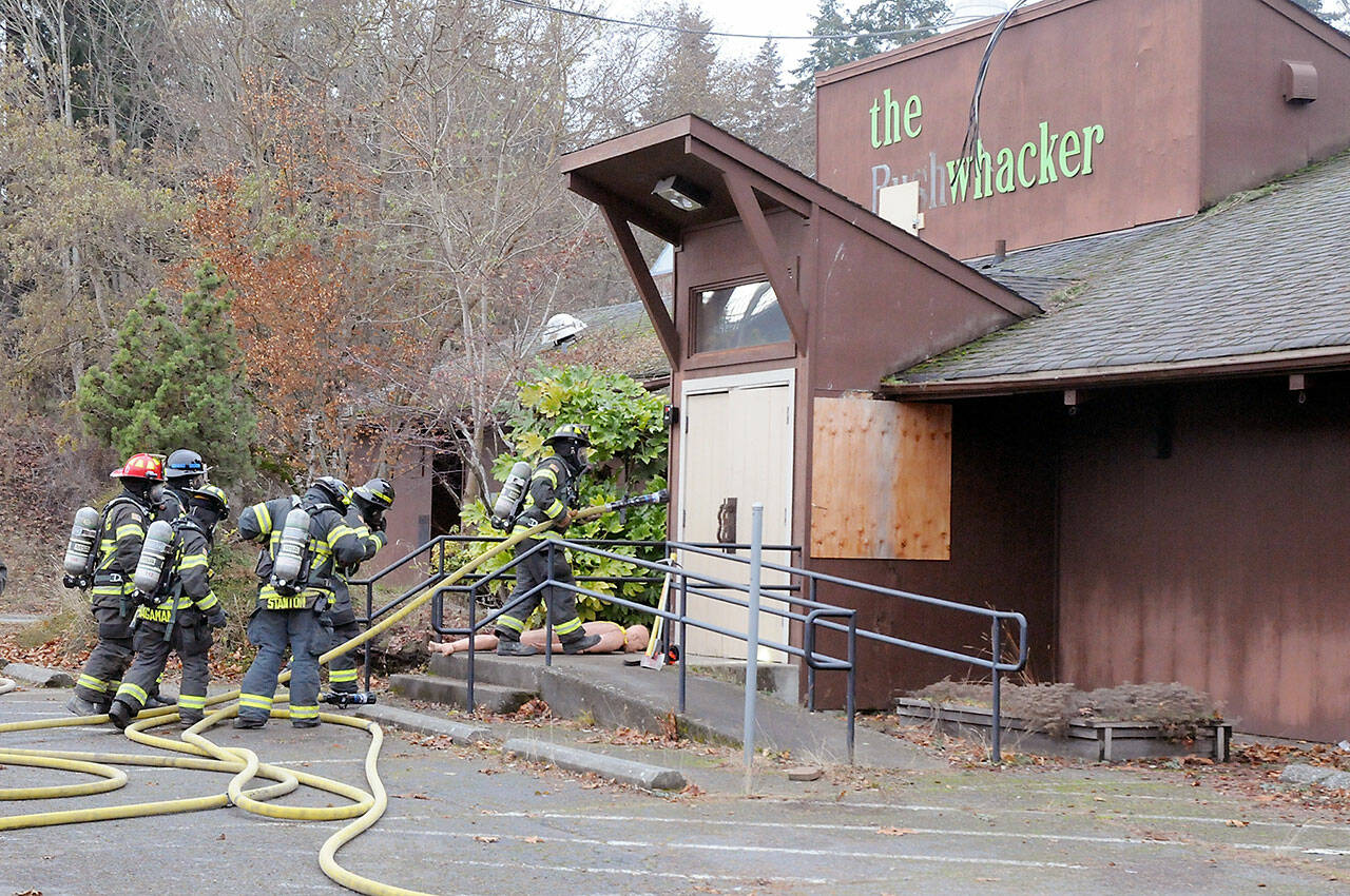 Port Angeles firefighters stage for entry into the former Bushwhacker restaurant during a fire training session on Friday. The exercise included filling the building with smoke to simulate the experience of a real fire and the use of a mannequin for rescue drills. Fire department Capt. Kelly Ziegler said the building would not be intentionally burned, but indicated that it was slated for eventual demolition. (KEITH THORPE/PENINSULA DAILY NEWS)