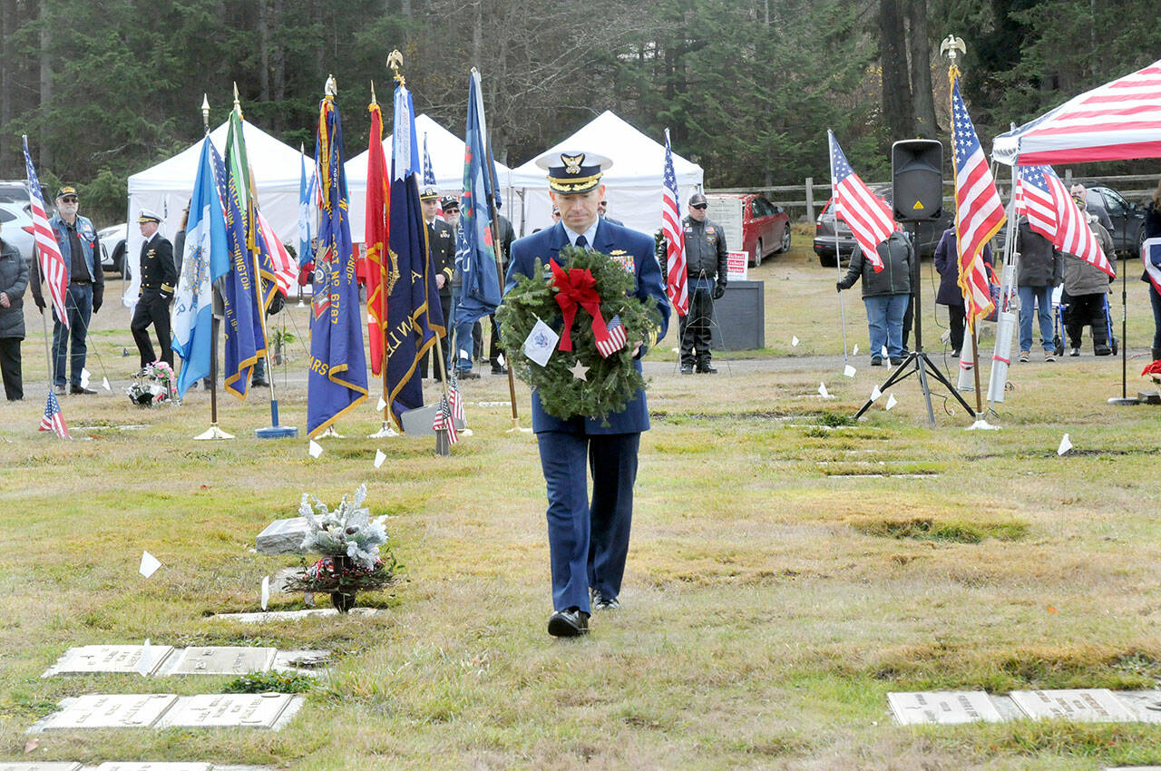 Cmdr. Brian Tesson, commanding officer of the U.S. Coast Guard Cutter Active, carries a wreath for the grave of Coast Guard veteran Harold Hanusa, who served during World War II, during Saturday’s Wreaths Across America ceremony at Mount Angeles Memorial Park in Port Angeles. The event, part of a national initiative to honor veterans of military service, saw individual branches of the military recognized during the ceremony followed by the placement of more than 2,300 wreaths for servicemen and women at six cemeteries across the North Olympic Peninsula. (Keith Thorpe/Peninsula Daily News)