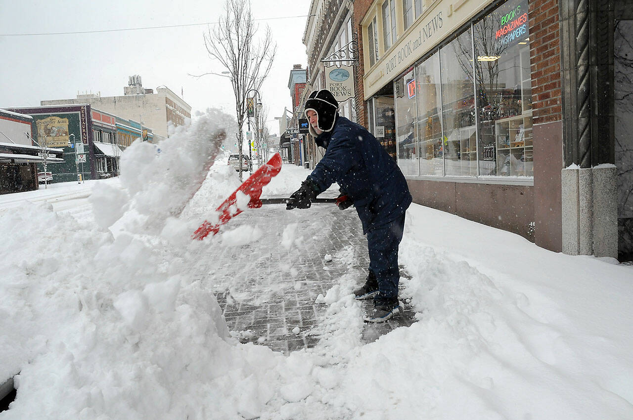 Alan Turner, co-owner of Port Book and News in downtown Port Angeles, shovels snow from in front of his business on Tuesday morning after most of the North Olympic Peninsula was blanketed in the overnight hours. (Keith Thorpe/Peninsula Daily News)