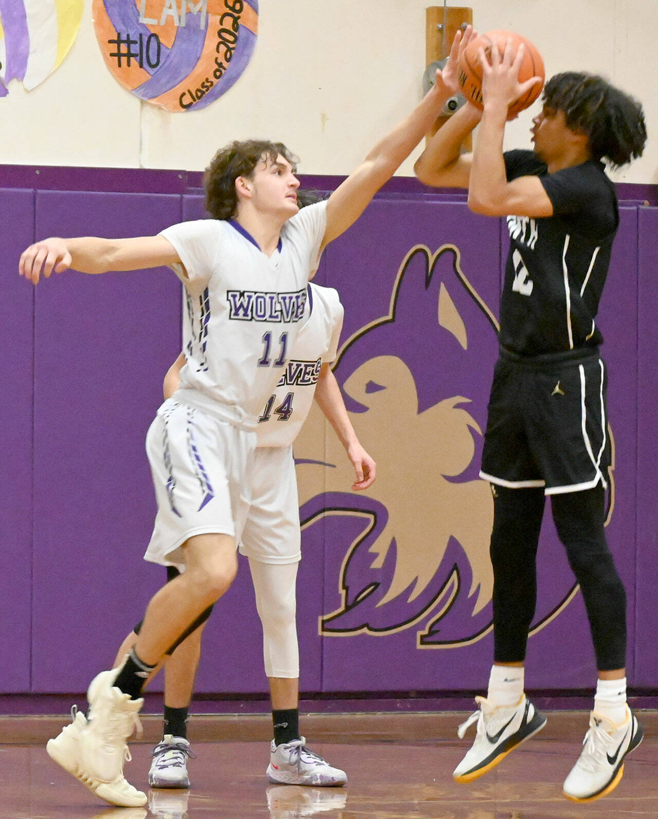 Sequim’s Charlie Grider gets his hands in the face of a jump shot taken by North Kitsap’s Harry Davies on Monday at Sequim High School. (Michael Dashiell/Olympic Peninsula News Group)