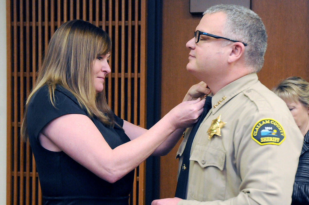 Incoming Clallam County Sheriff Brian King, right, receives his sheriff star from his wife, Brenda King, after he was sworn into office by Superior Court Judge Lauren Erickson on Wednesday at the Clallam County Courthouse. (Keith Thorpe/Peninsula Daily News)