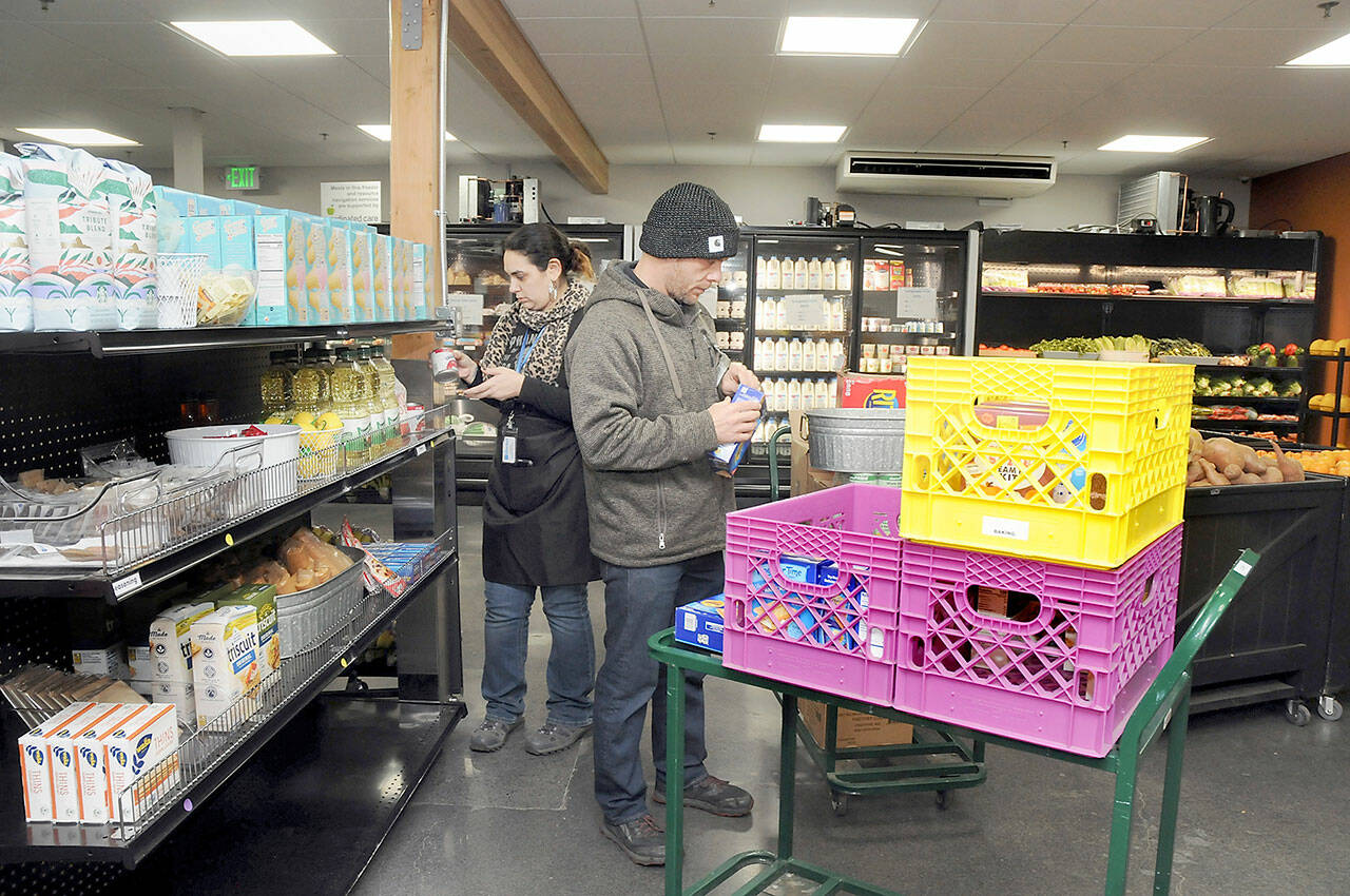 Analise Graziani, manager of The Market at the Port Angeles Food Bank, left, and Adam Frandsen, a food bank staff member with Americorps, stock shelves at The Market before opening to the public on Thursday. (KEITH THORPE/PENINSULA DAILY NEWS)