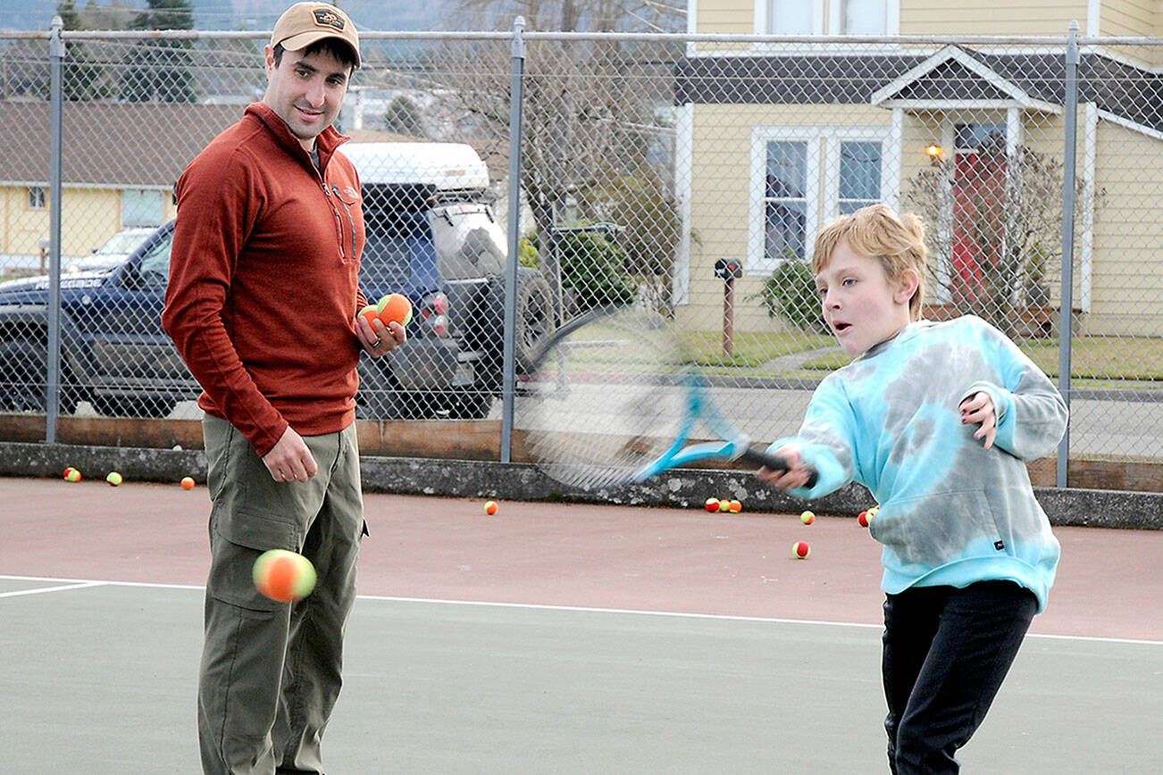 Noah Larsen, 9, of Port Angeles practices his forearm swing with the help from tennis instructor Jeff Gonzales on Thursday in Port Angeles. The pair worked with practice balls on the courts at Erickson Playfield. (Keith Thorpe/Peninsula Daily News)