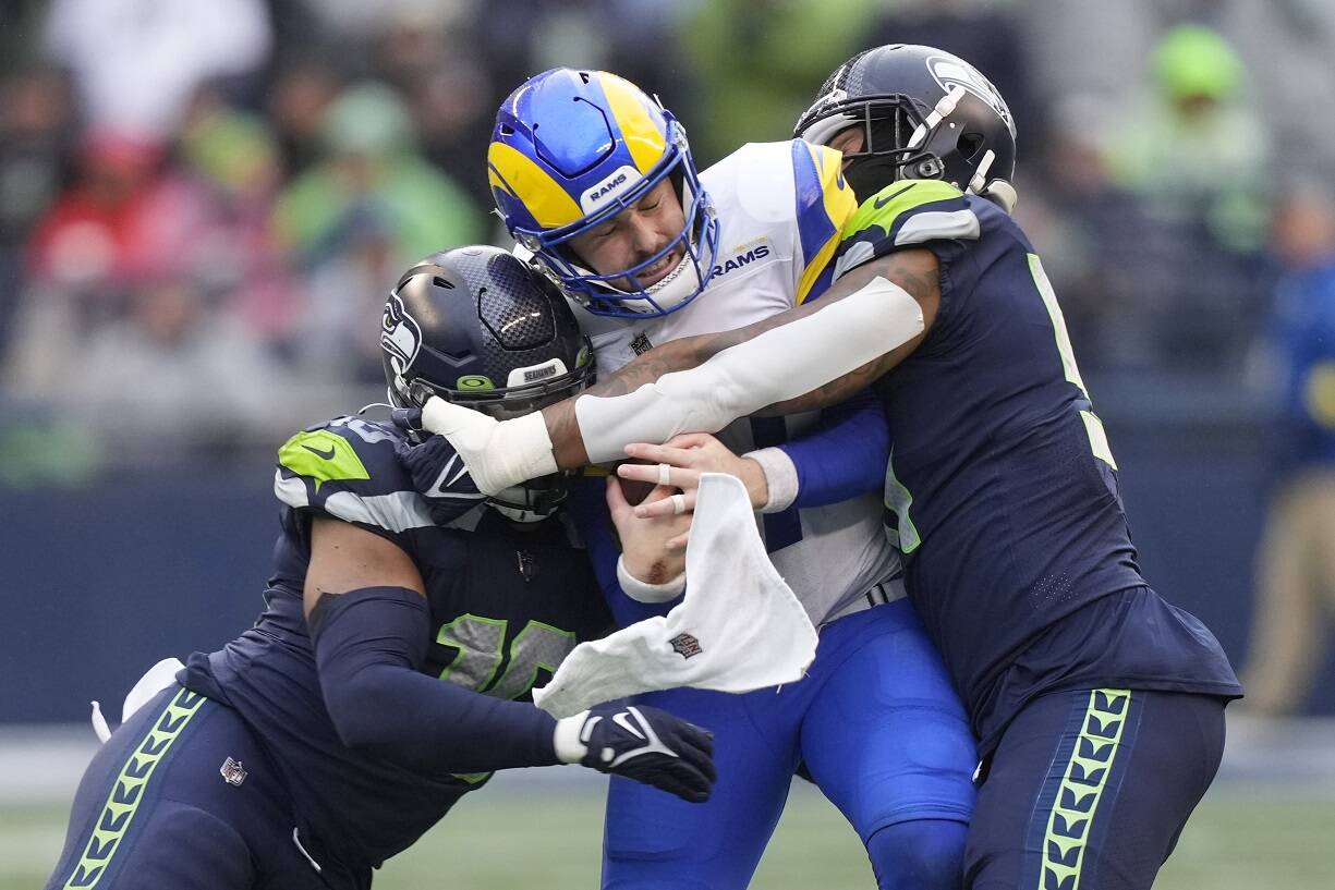 Los Angeles Rams quarterback Baker Mayfield, center, is tackled by Seattle Seahawks linebackers Bruce Irvin, right, and Uchenna Nwosu during the second half of an NFL football game Sunday, Jan. 8, 2023, in Seattle. (AP Photo/Stephen Brashear)