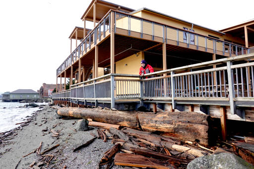 Robert Flagg of Port Townsend looks down at a massive log that is jammed under a section of the pier at the Northwest Maritime Center on Monday. The log was washed in by recent king tides and winds and caused minor damage to the railing, which has been repaired. (Steve Mullensky/for Peninsula Daily News)