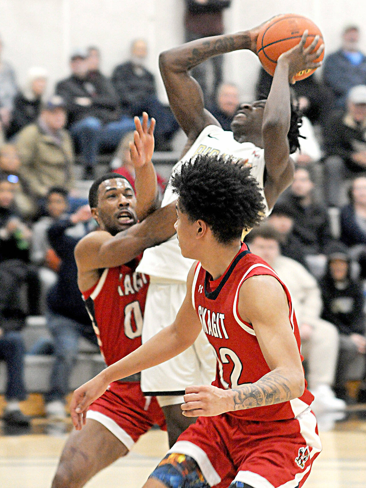 KEITH THORPE/PENINSULA DAILY NEWS
Peninsula's Ese Onakpoma, center, shoots pass Skagit Valley defenders Omari Maulana, left, and Hodges Flemming on Wednesday night's game in Port Angeles.