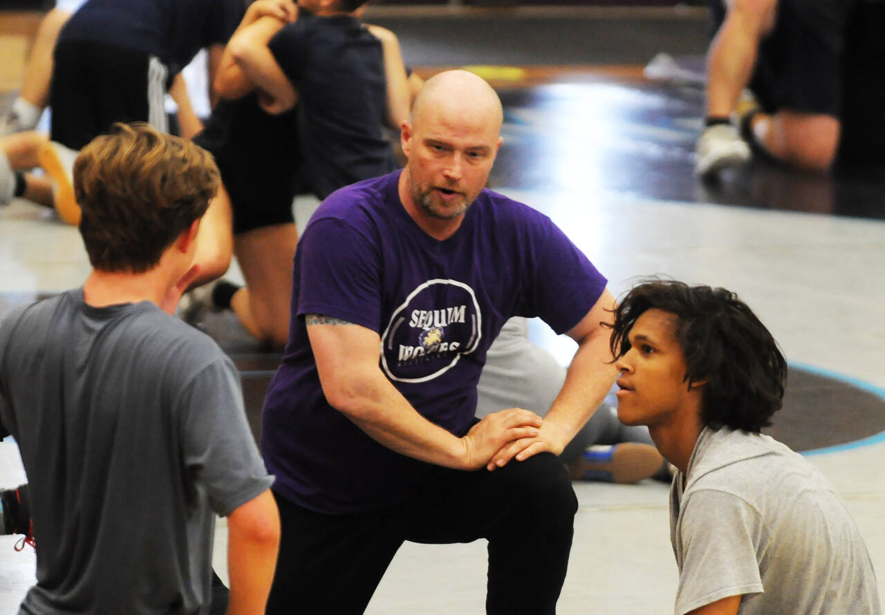 Sequim High wrestling coach Chad Cate works with campers at a camp in Sequim in July 2022.