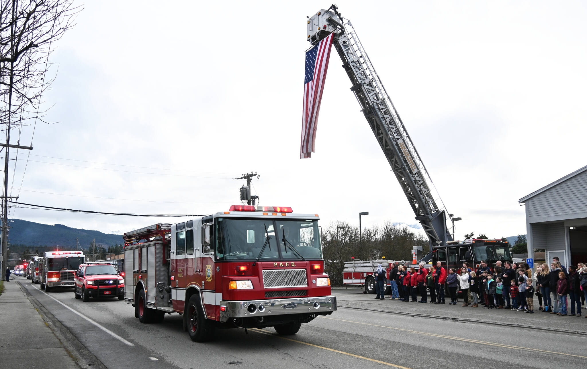 Clallam County Fire District 3 personnel, along with other Olympic Peninsula fire departments, first responders and firends, honor Fire District 3 Capt. Charles “Chad” Cate with a procession of vehicles through Sequim on Jan. 13. Here, the procession passes by District 3’s station on North Fifth Avenue in Sequim. Cate was found deceased in his bunk in the early morning hours of Jan. 12. (Michael Dashiell/Olympic Peninsula News Group)