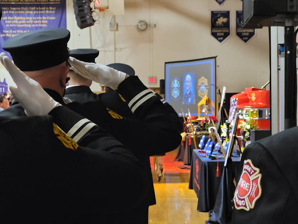 Firefighters pay tribute to Capt. Charles “Chad” Cate at a memorial service at Sequim High School on Saturday. (Michael Dashiell/Olympic Peninsula News Group)