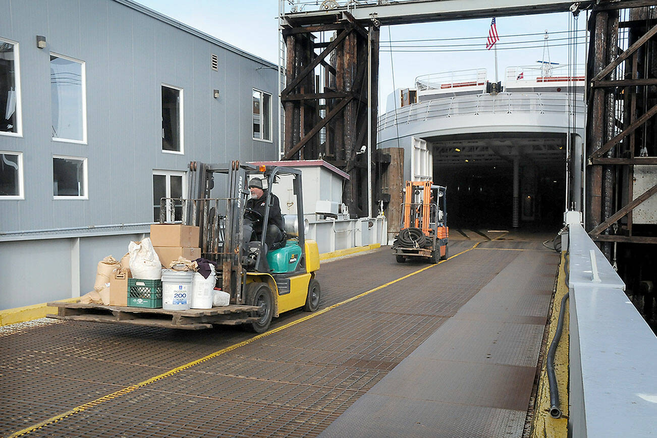 Able seamen Doug Reader, front, and Brandon Melville drive forklifts as they offload equipment from the ferry MV Coho after its return to Port Angeles from annual dry dock maintenance in Anacortes on Wednesday. The ferry is scheduled to resume regular service between Port Angeles and Victoria today. (Keith Thorpe/Peninsula Daily News)