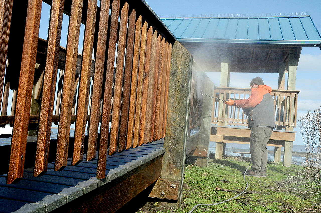 Tanner Germeau, a maintenance worker with the Clallam County Parks Department, uses a pressure washer to clean portions of an observation deck at Dungeness Landing County Park north of Sequim on Tuesday. The deck is a popular spot for bird watching as part of the Great Washington State Birding Trail. (Keith Thorpe/Peninsula Daily News)