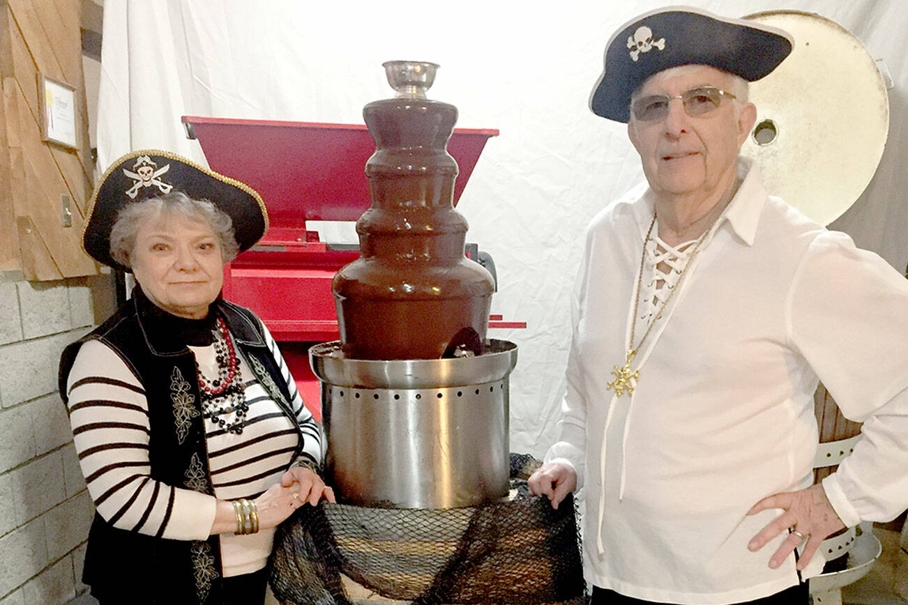 FairWinds Winery owners Judy and Micheal Cavett pose with the chocolate fountain in their pirate-themed Port Townsend Red Wine and Chocolate event.