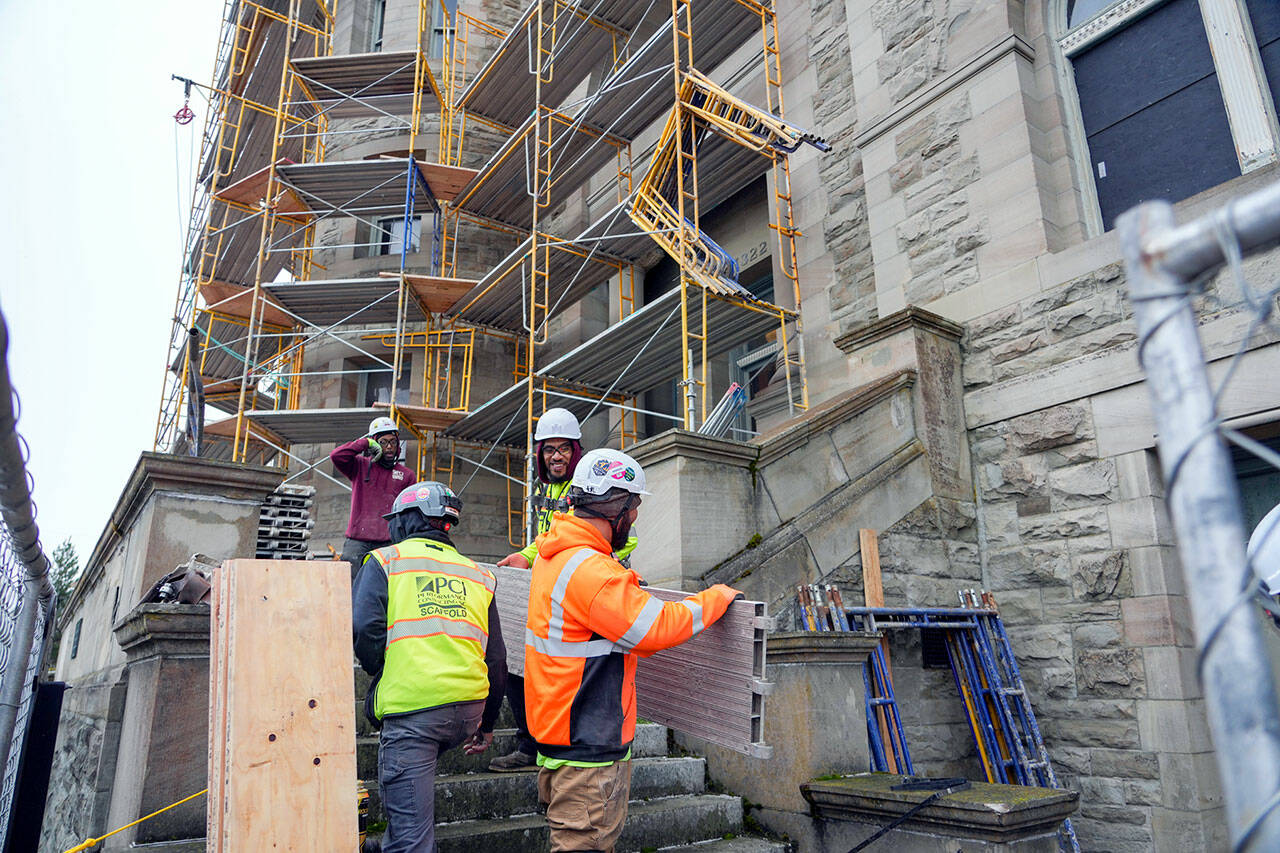 Workers for Hilger Construction, out of Tacoma, move parts of scaffolding that will soon encase the historic Post Office and Customs House in Port Townsend. The building, constructed in 1892, is undergoing a months-long preservation project to replace aging and nonfunctioning windows. (Steve Mullensky/for Peninsula Daily News)