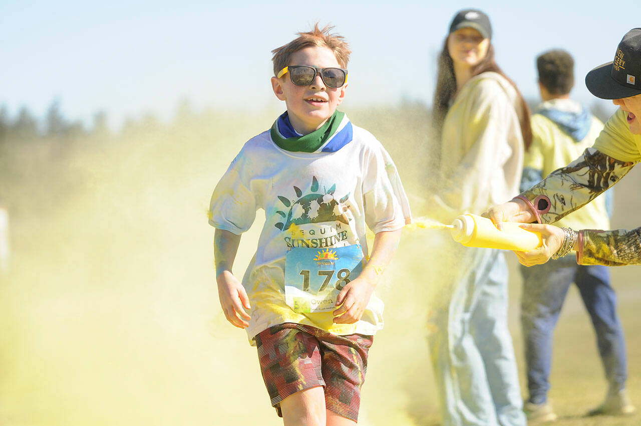 Owen DeAngelo grins as he gets a touch of yellow at the last color station at the Sun Fun Color Run 5K in 2022 at the Albert Haller Playfields just north of Carrie Blake Community Park. Entries remain open for the 1K and 5K run/walk races on Saturday. (Michael Dashiell/Olympic Peninsula News Group)