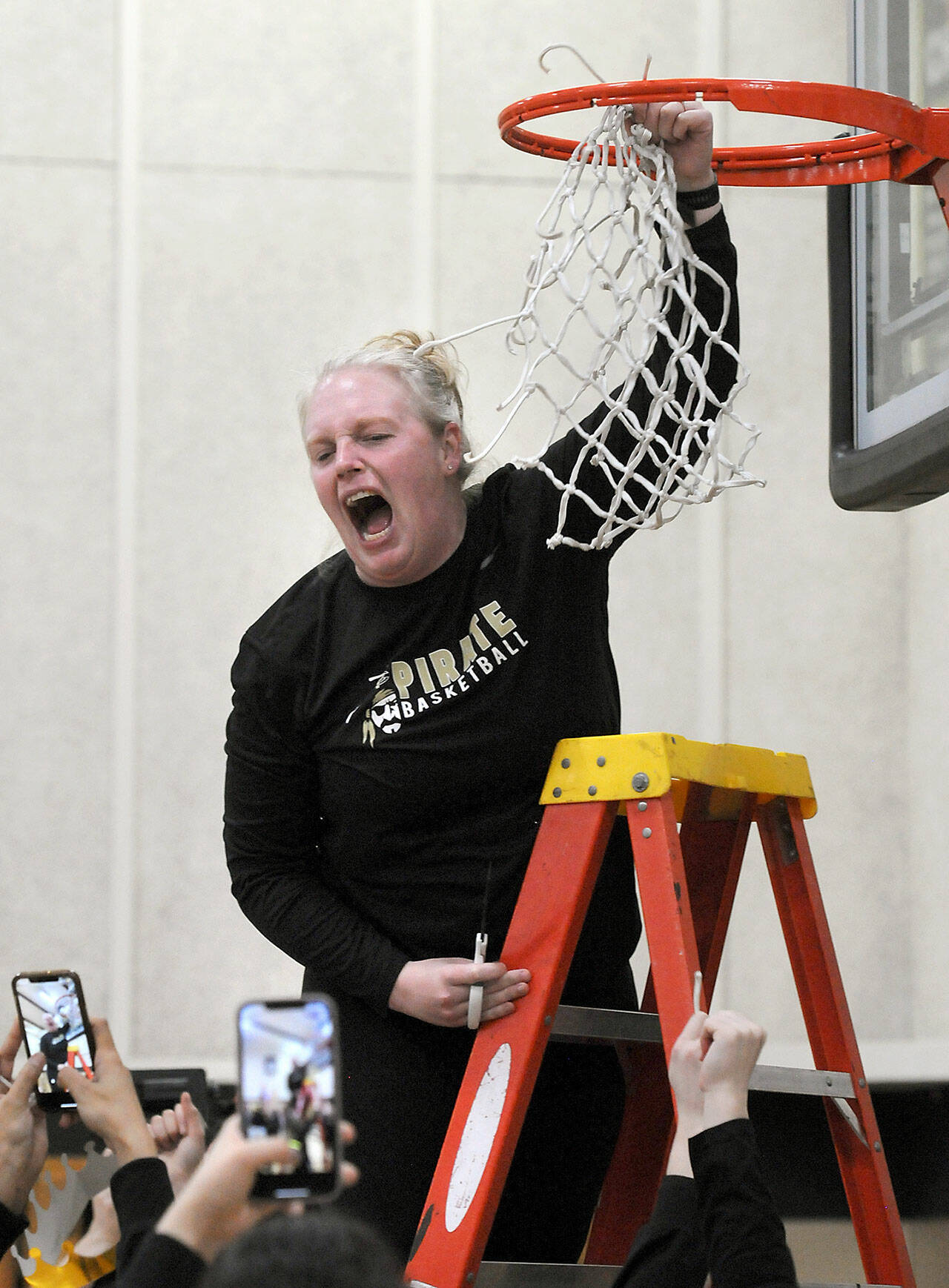Peninsula Pirates head coach Ali Crumb emits a scream of excitement as she cuts down the net after her team clinched the NWAC North Region championship by defeating Everett on Wednesday in Port Angeles. (Keith Thorpe/Peninsula Daily News)