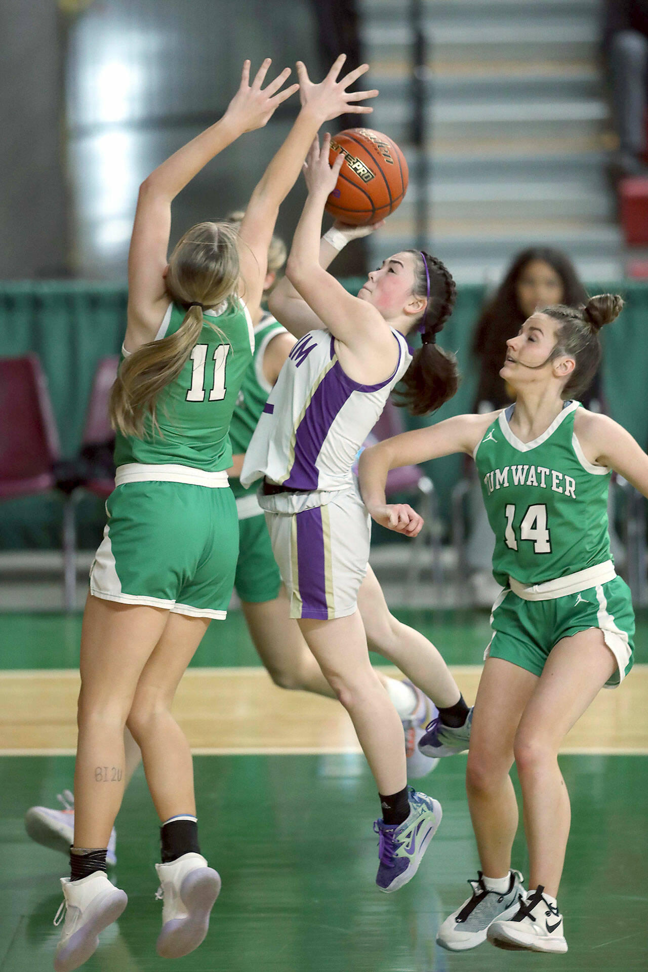 David Willoughby/for Peninsula Daily News Sequim’s Hannah Bates attacks the rim while Tumwater’s Kylie Waltermeyer, left, and Hadley Woods defend during the Wolves’ 38-24 state victory Friday at the Yakima Valley SunDome.