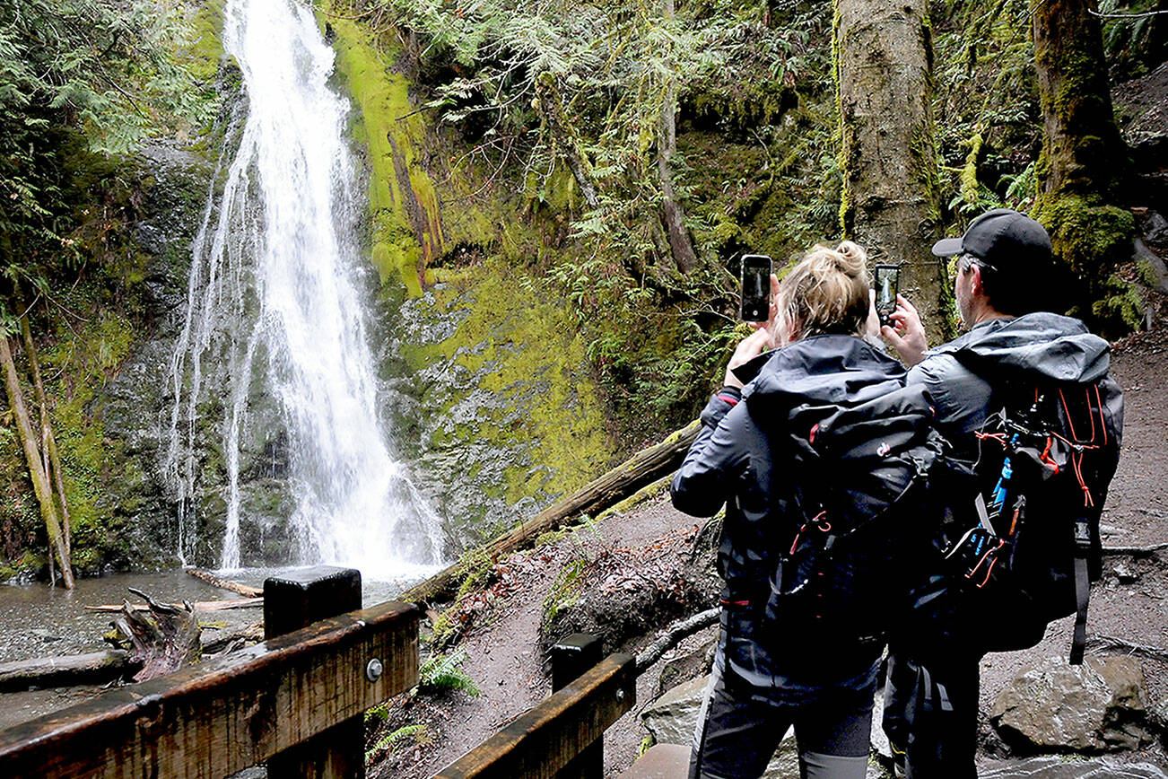 Larissa Lupp of Frankfurt, Germany, left, and Alex Nebel of Graz, Austria, take cellphone photos of Madison Creek Falls on the north edge of Olympic National Park on Friday. The pair were exploring features of the Elwha River Valley southwest of Port Angeles during a visit to the park. (Keith Thorpe/Peninsula Daily News)