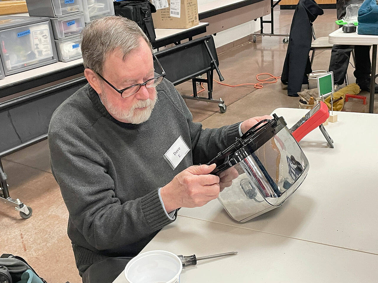Dave Ehnesbusake examines a toaster that won’t work at the Port Townsend Marine Science Center’s Repair Cafe on March 11. This is the second year Ehnesbuske has volunteered at the event, which promotes repairing items rather than throwing them away, sharing knowledge and fostering community. (Paula Hunt/Peninsula Daily News)
