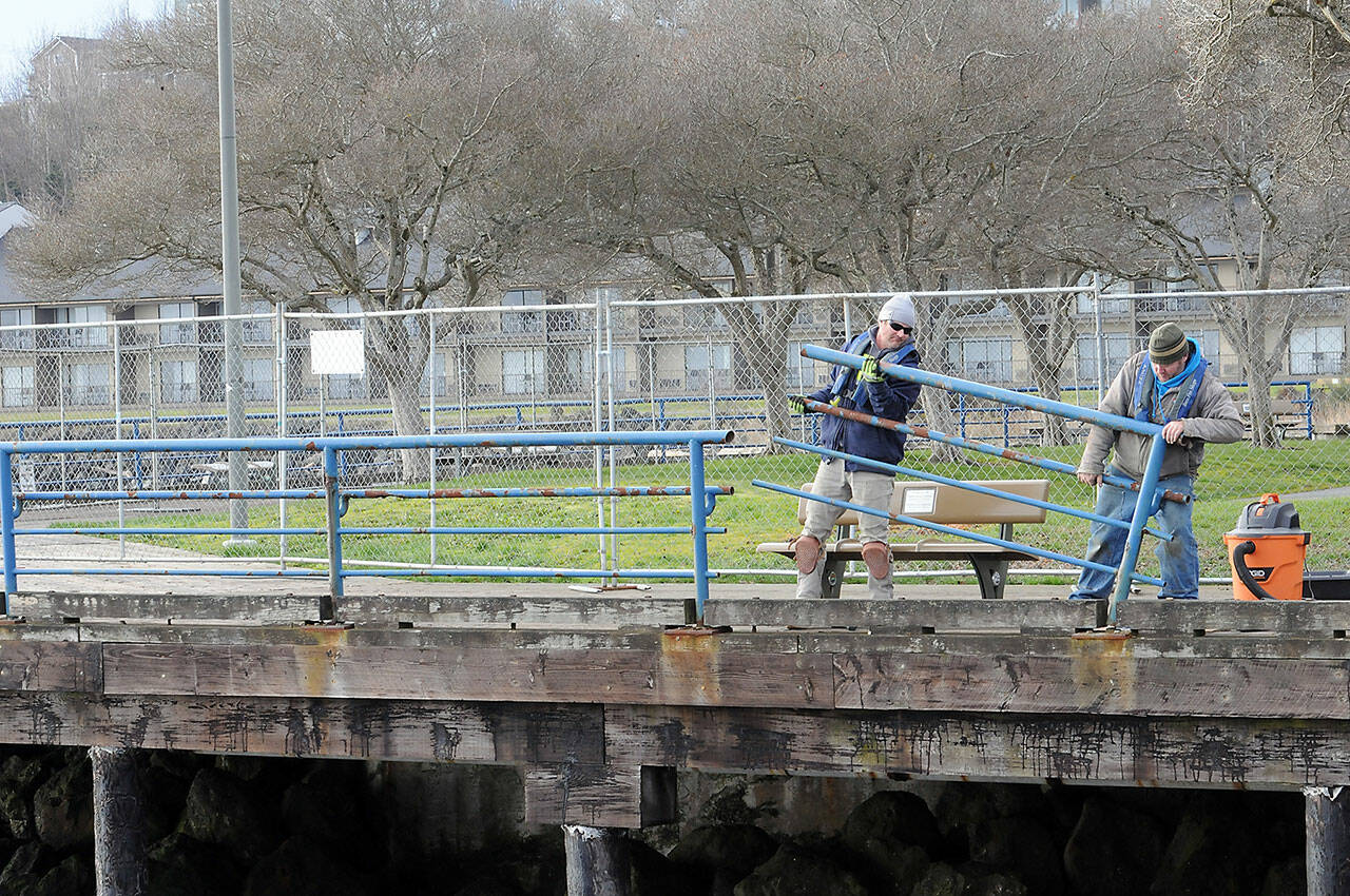 Brian Tucker, left, and Kevin Smith, workers with the Sequim branch of Neely Construction Co., remove a section of rusted railing at Port Angeles City Pier on Thursday. (KEITH THORPE/PENINSULA DAILY NEWS)