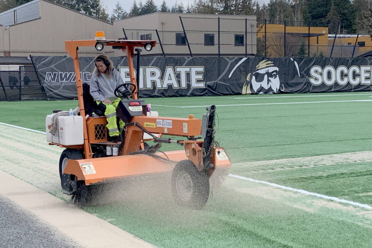 Melisa Kisner, employee of FieldTurf from Buckley, works on the new Peninsula College soccer field surface earlier this month. The college is holding a ribbon-cutting ceremony Wednesday for the new surface. (Peninsula College)