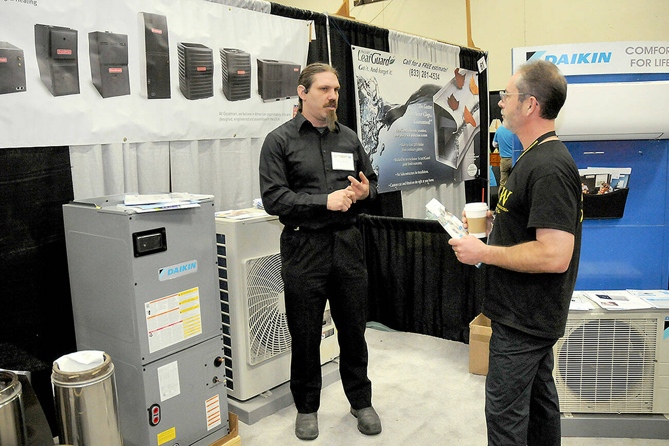 John Graham of Sequim, right, talks with Richard Fife, owner of Port Angeles-based Strait Comfort Systems, at the 38th annual KONP Home Show on Saturday at Port Angeles High School. The event featured dozens of exhibitors and displays centered on homes, home improvement and lifestyles. (Keith Thorpe/Peninsula Daily News)