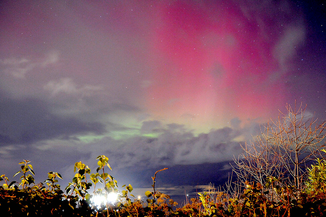 KEITH THORPE/PENINSULA DAILY NEWS
Curtains of red and green peek out from behind a bank of clouds as the aurora borealis illuminates the sky north of Port Angeles on Thursday evening. Otherwise known as the northern lights, the aurora was the result of a severe, G4-category geomagnetic storm in the Earth's atmosphere triggered by charged particles emanating from the Sun. Auroras were widely visible Thursday across Canada and northern portions of the United States. Forecasts say they might be visible tonight.