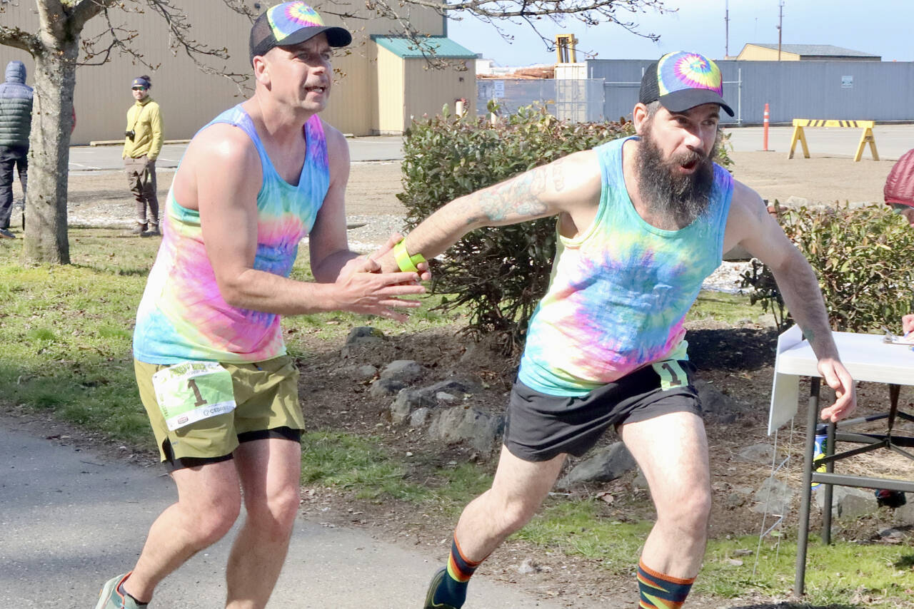 Subalpine Tees Race Team runner Chris Cummings hands the baton to brother and teammate Jon Cummings at the Port Angeles Yacht Club transfer zone during Saturday's Frosty Moss Relay. The event that stretches from the Sol Duc Valley to Blyn featured 48 relay teams and four individuals. The Subalpine Tees finished sixth in the 80-mile race. (Dave Logan/for Peninsula Daily News)