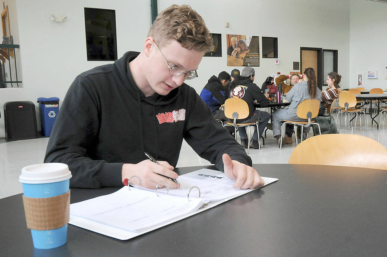 Bradley Taylor of Sequim takes time for classwork in the High School+ program on Tuesday in the Pirate Union Building on the Port Angeles campus of Peninsula College. Tuesday marked the beginning of the school’s spring academic quarter, which runs through June 16. (Keith Thorpe/Peninsula Daily News)
