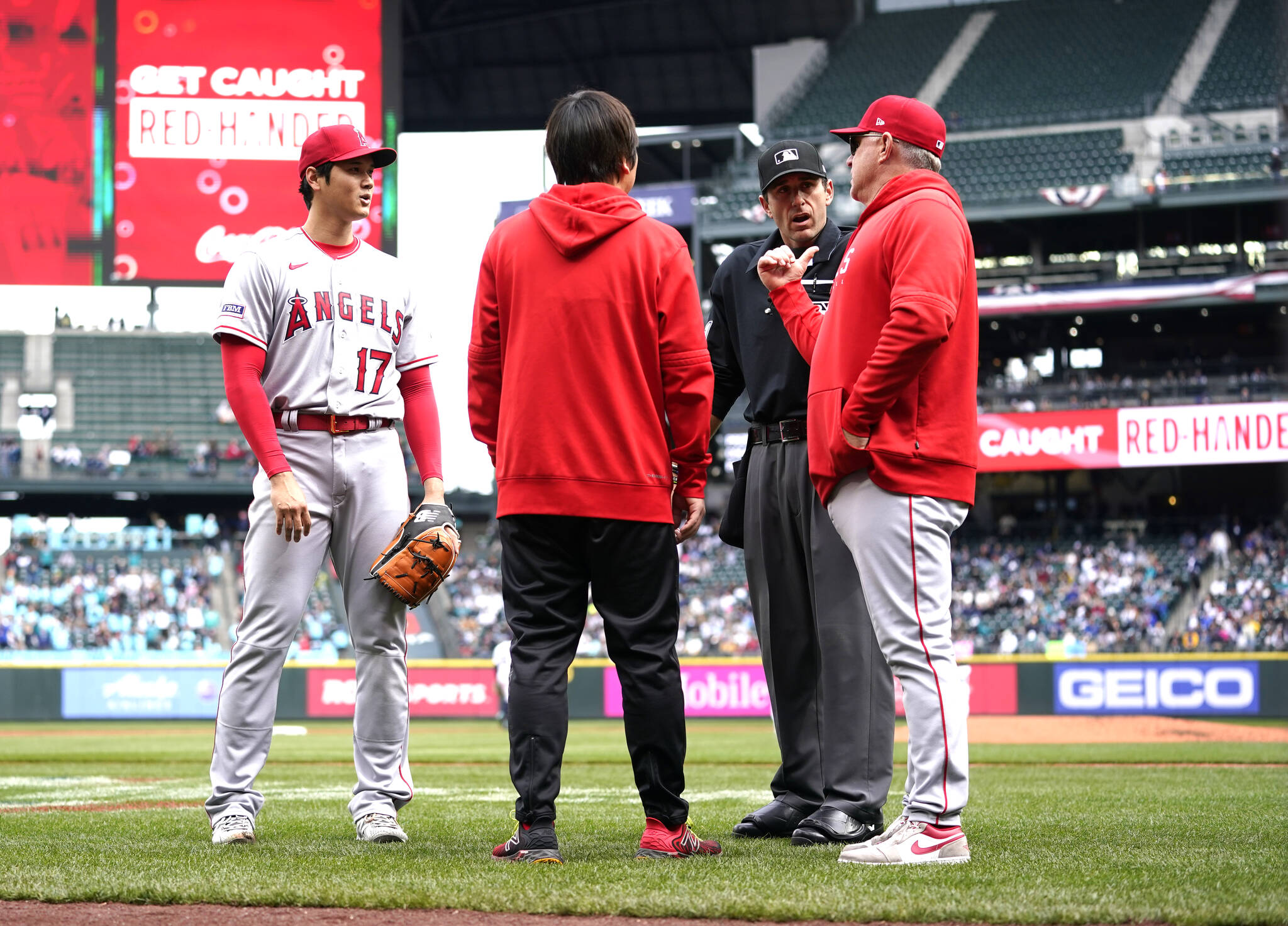Los Angeles’ Shohei Ohtani, left, talks with interpreter Ippei Mizuhara, home plate umpire Pat Hoberg and manager Phil Nevin after he was called for a pitch clock violation against the Seattle Mariners. (The Associated Press)