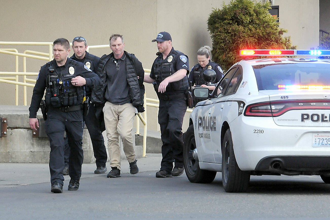 Police escort a man, center, who was alleged to have brandished a gun in the 48º North Waterfront Restaurant next to the Red Lion Hotel on Saturday. The incident prompted evacuation of the restaurant while closing down the 100 block of North Lincoln Street. (Keith Thorpe/Peninsula Daily News)