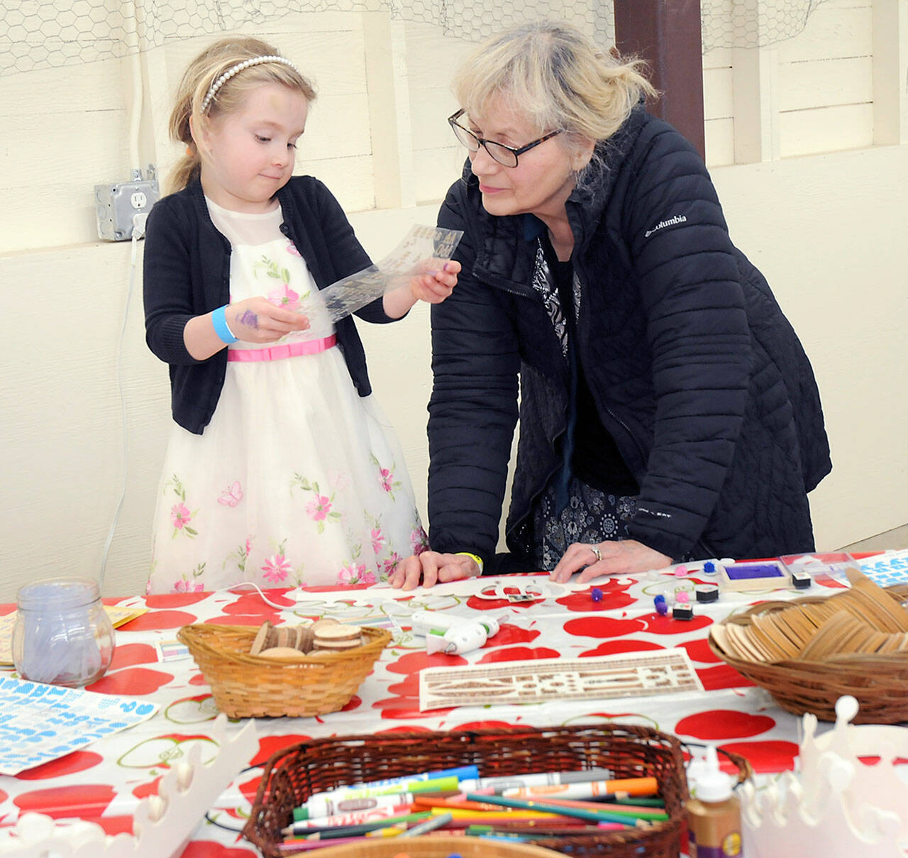 Ida Shantz, 5, of Port Angeles looks over a sheet of stenciled letters with her grandmother, Patricia Kessler of Woodburn, Ore., at a cardboard crown craft table during Saturday’s Barn Dance at the Clallam County Fairgrounds to benefit the Five Acre School north of Sequim. The dance also included food, entertainment, children’s activities and a silent auction. (Keith Thorpe/Peninsula Daily News)