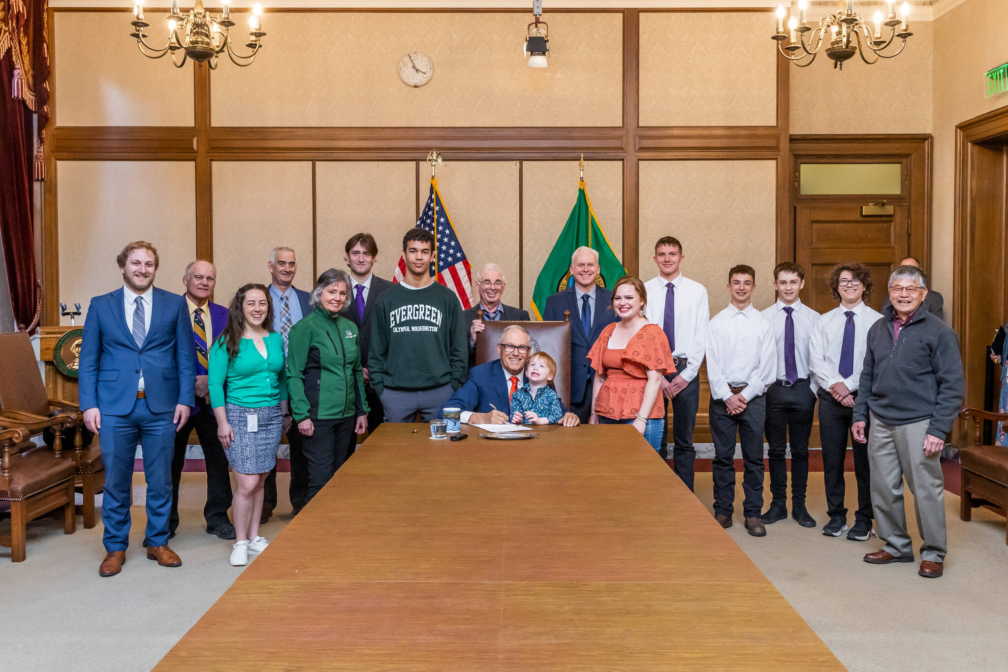 Photo courtesy of Randy Tomaras/Gov. Jay Inslee’s office / Gov. Jay Inslee, center, signs Substitute Senate Bill No. 5687 on April 25 — legislation called the Charles Cate II Act that bolsters the creation and support of postsecondary wrestling grant programs. Joining Inslee are Cate’s son Charley and wife Renee. Behind Inslee is primary bill sponsor Sen. Kevin Van De Wege and Sequim wrestling advocate Randall Tomaras, along with wresters and wrestling advocates. At far right is SHS wrestling coach Steve Chinn.