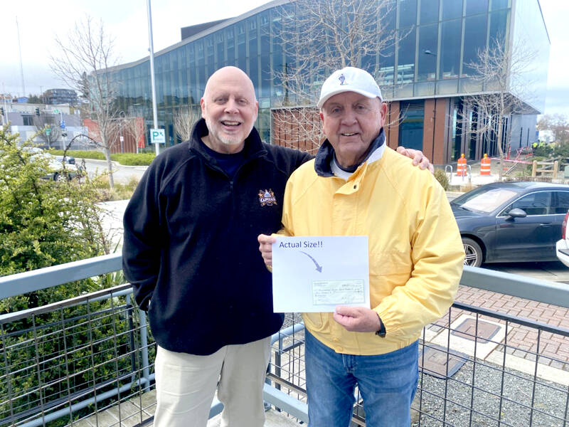 Ed Bedford, Port Angeles High School Class of 1965 and owner of Bedford Soda, stands with Chris Fidler, project director for the Field Arts & Events Hall, holding a $25,000 check for the venue’s capital campaign.