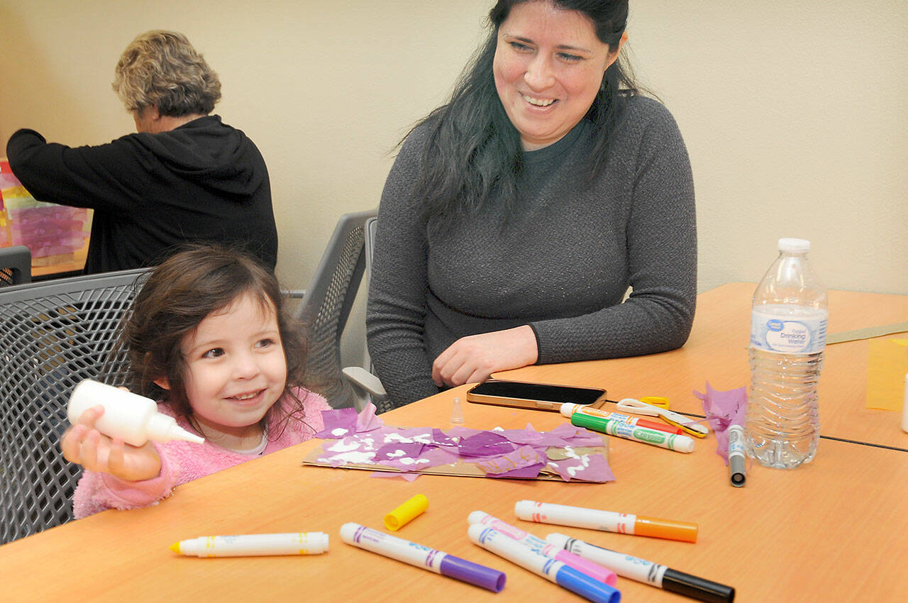 Arya Morrison, 3, grins while creating an art project as her mother, Janeth Morrison of Port Angeles, looks on during Saturday’s Dia del Niño, or Day of the Child, at the Port Angeles Public Library. The event, based upon an annual celebration in Mexico, was created to recognize the importance of children in society and to promote youth literacy. (Keith Thorpe/Peninsula Daily News)