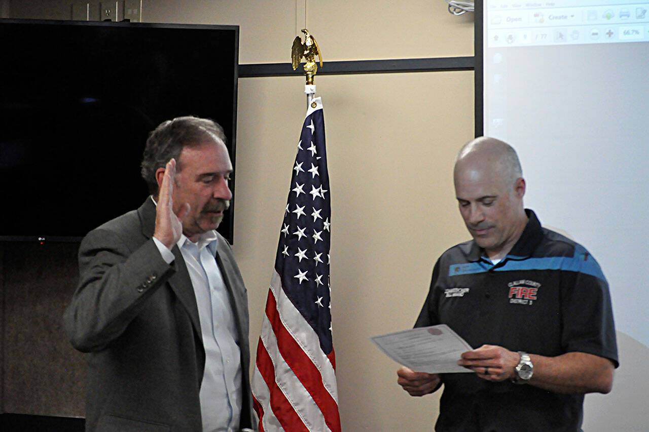 Fire commissioner Bill Miano, right, swears in appointed commissioner Mike Mingee on May 2 during a meeting of the Clallam County Fire District 3’s board of commissioners. Mingee told commissioners in April he’s planning to file to run for the position this month. (Matthew Nash/Olympic Peninsula News Group)