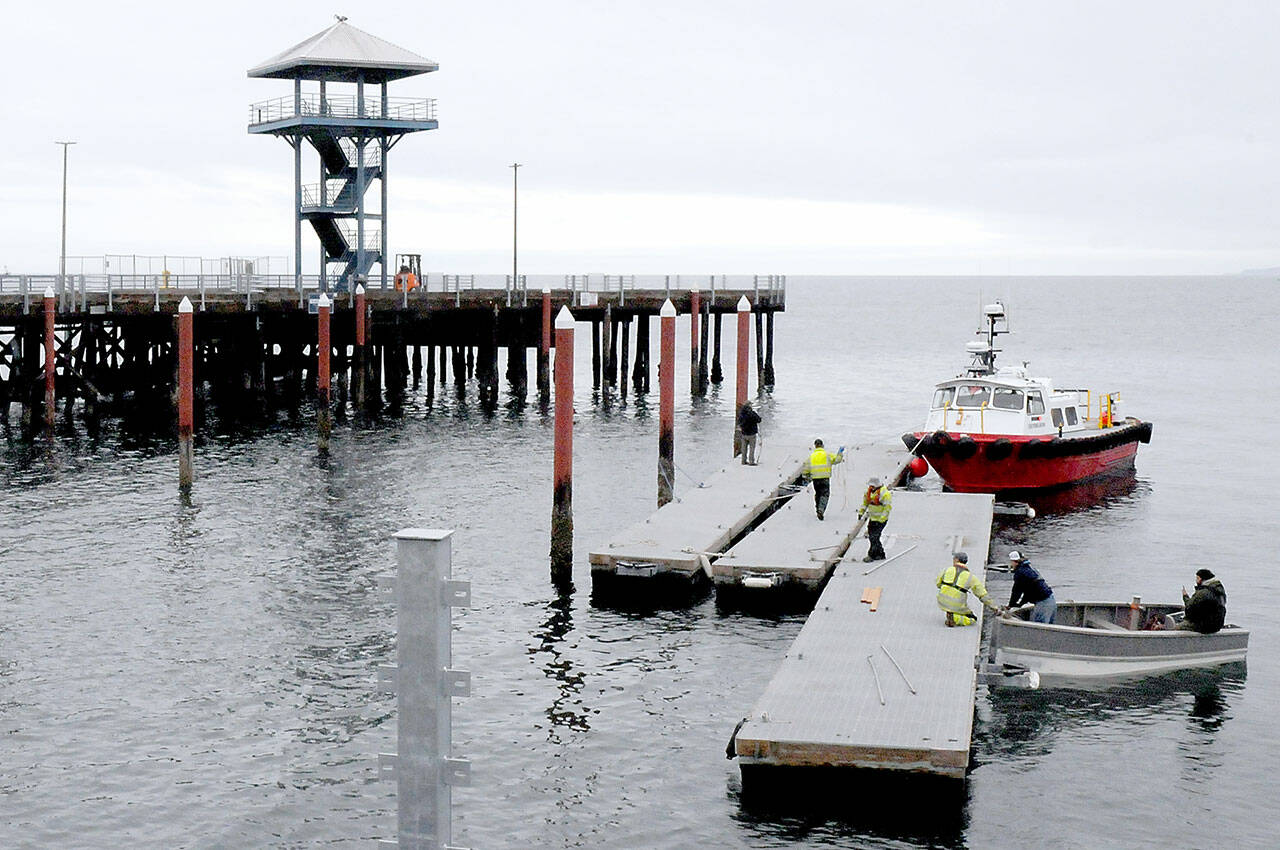 Port Angeles Parks and Recreation Department workers prepare floating dock sections for installation after they were barged across Port Angeles Harbor from storage to Port Angeles City Pier on Thursday. The docks, used for transient moorage, have not been deployed since 2021, when a primary float was damaged by a storm. Floats are scheduled to be in place this weekend, although the gangways from the upper pier deck will not be lowered into position until next week. The utility vessel Cheyenne Arrow assisted with bringing the sections across the harbor. (Keith Thorpe/Peninsula Daily News)