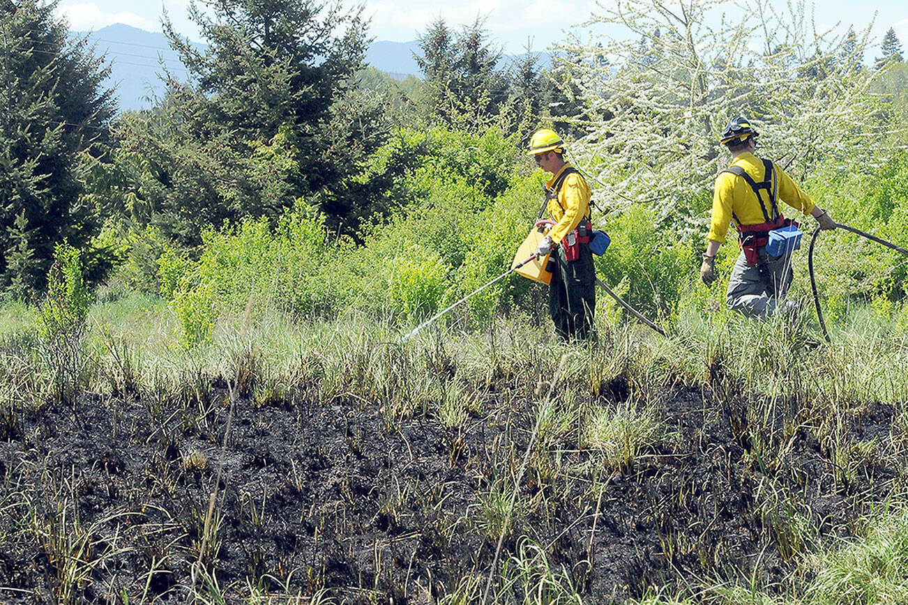 KEITH THORPE/PENINSULA DAILY NEWS
Clallam County Fire District 2 firefighters Chris Dalen, left and Zach Gear put out hot spots around the perimeter of a brush fire near 2333 Lower Elwha Road on Friday. The fire burned an area approximately 200 feet by 200 feet while scorching a tree and threatening a nearby mobile home.
