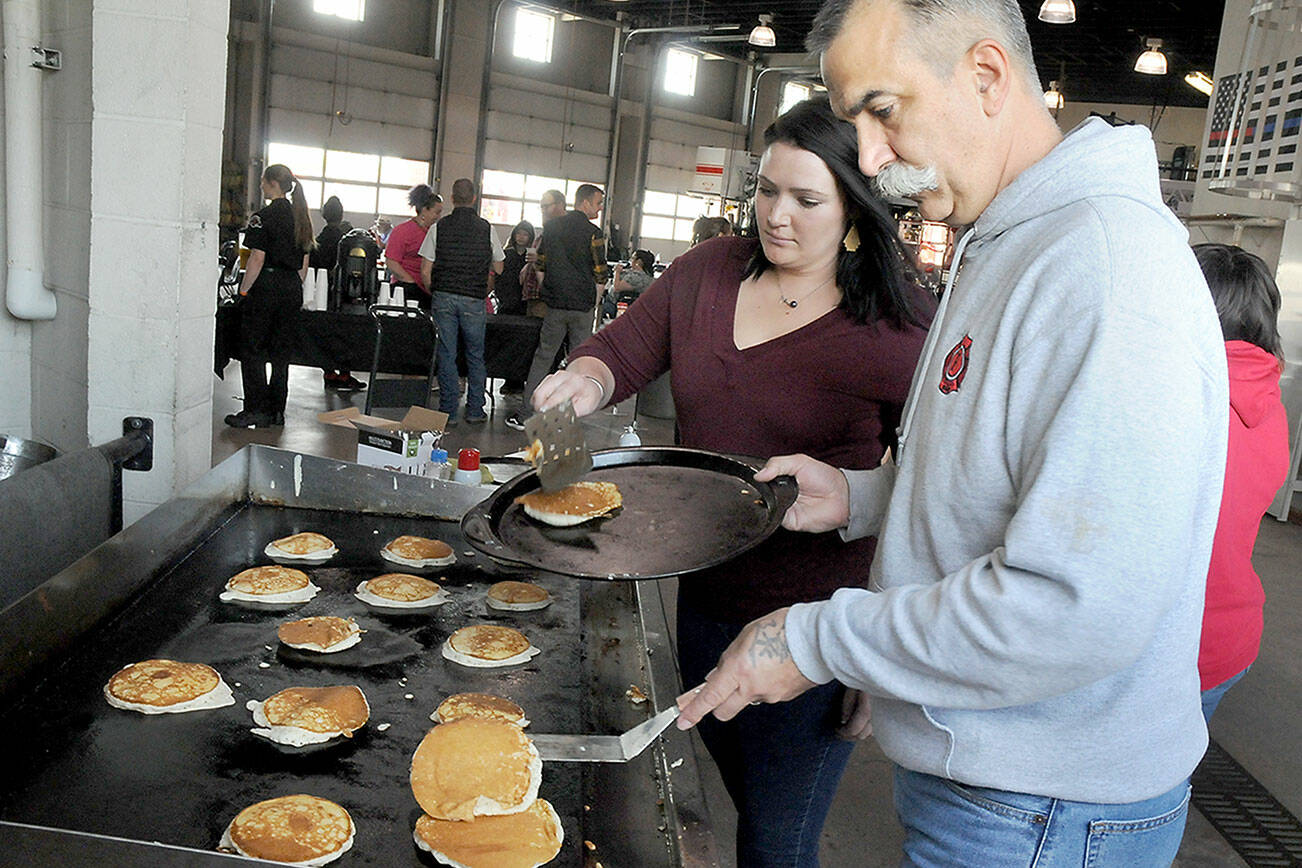 Port Angeles Fire Department paramedics Kristin Fox, left, and Brian Gerdes flip pancakes during the department’s annual pancake breakfast on Saturday at the fire hall. The event, which included a complete breakfast with beverage, was a fundraiser for fire department scholarships and community outreach. (Keith Thorpe/Peninsula Daily News)